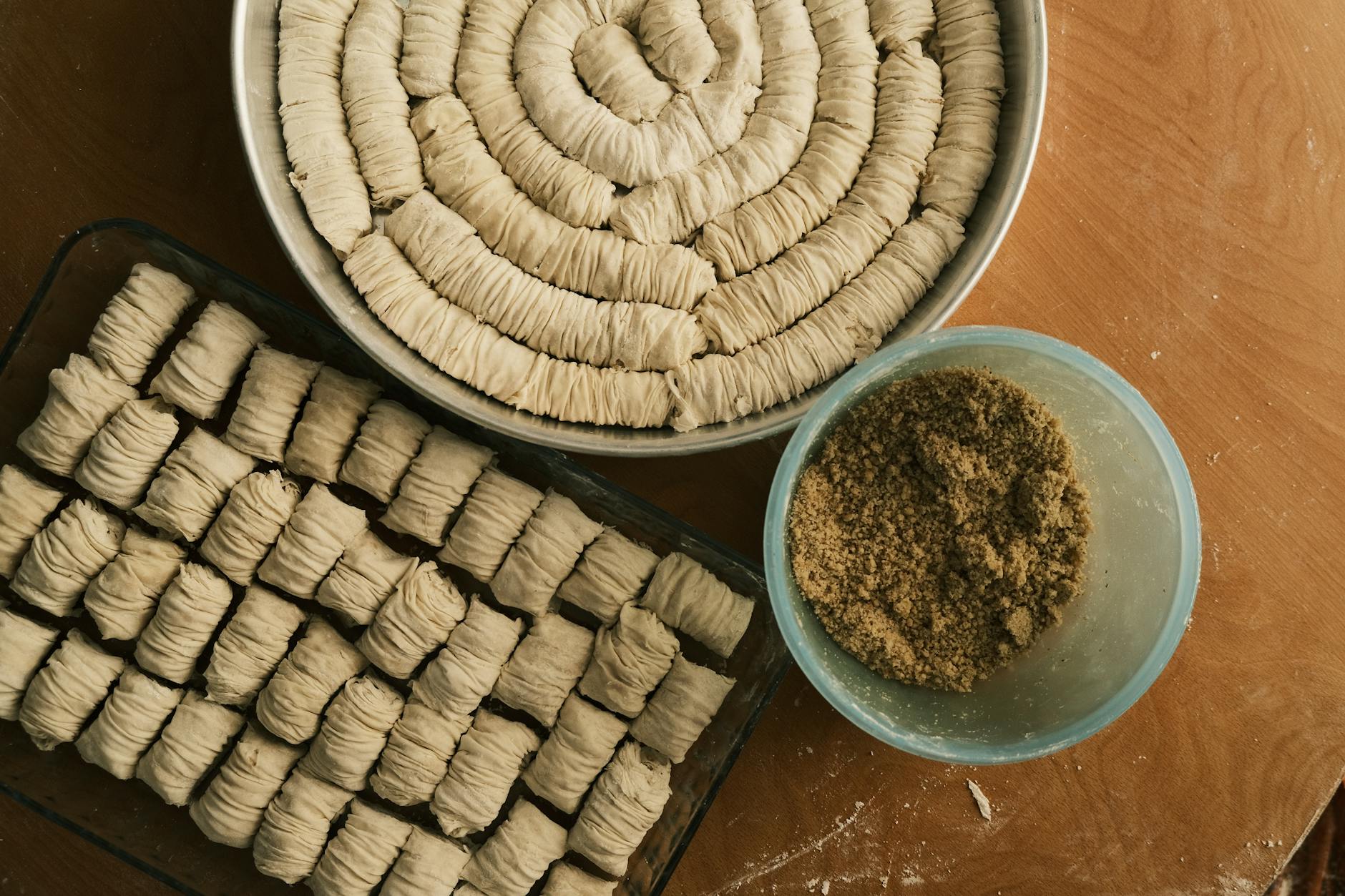 A top view of rolled dough and toppings for homemade pastries arranged on a wooden surface. — el dulce árabe en espiral