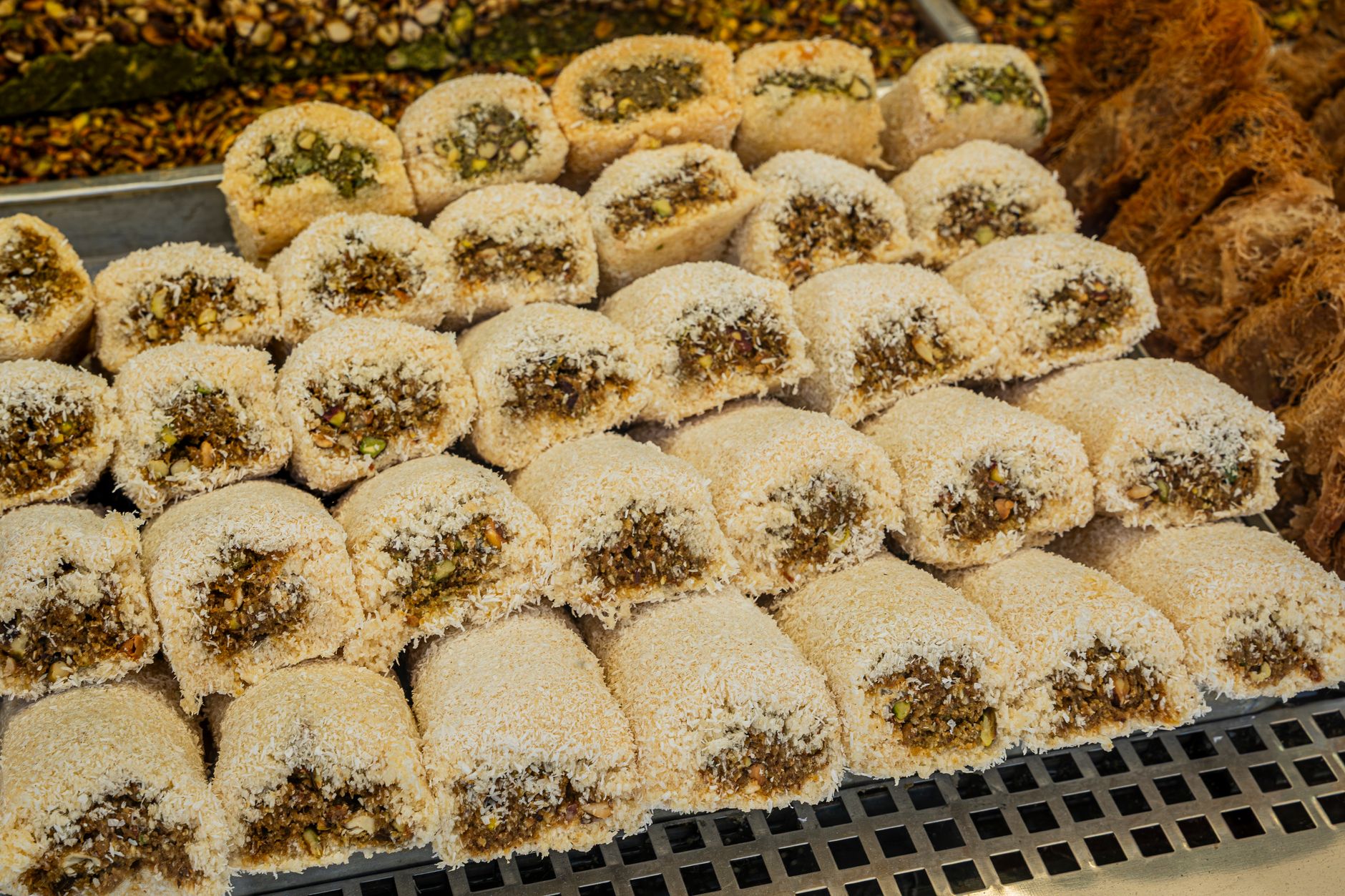 Rows of Middle Eastern pastries filled with nuts and coconut, perfect for dessert lovers.